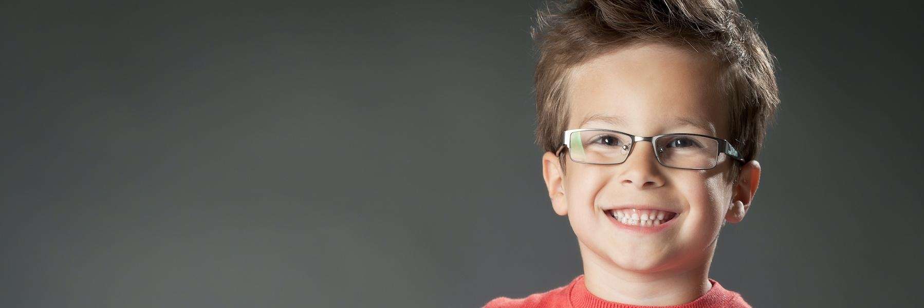 Boy wearing eyeglasses smiles with his clean small teeth in Block VIC