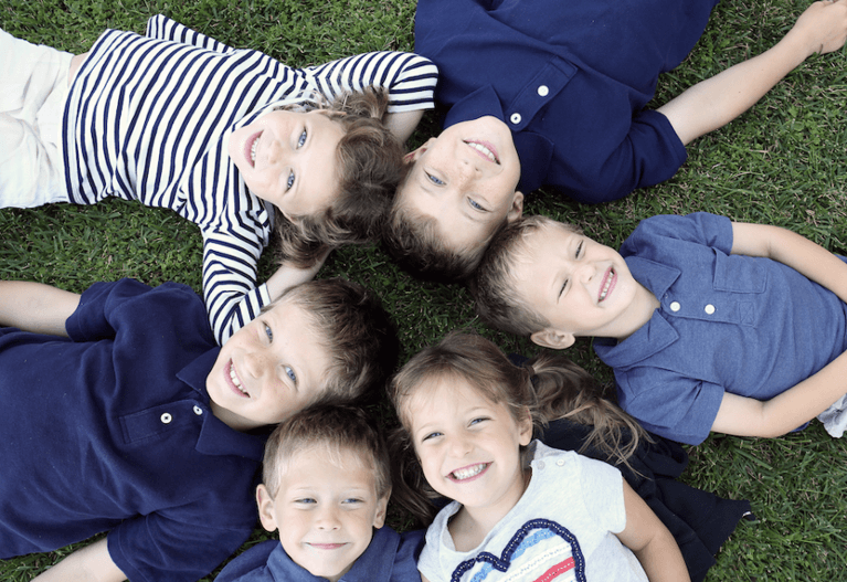 Group of children in Black Rock VIC resting on the ground, smiling