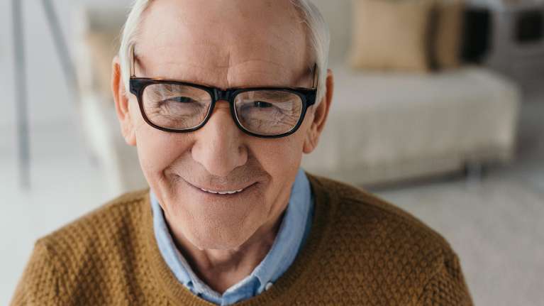 old man wearing eyeglasses smiles with his dental implant in Black Rock, VIC