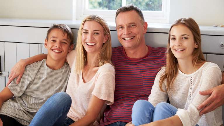 Family sitting by the window smiling with their entire set of good teeth in Black Rock